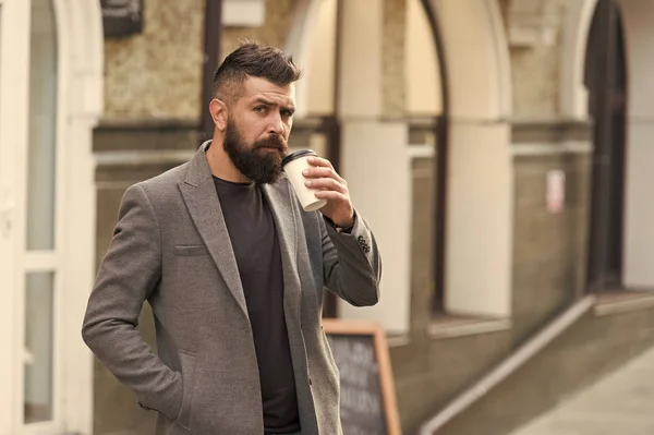 Drinking coffee on the go. Businessman lumbersexual appearance enjoy coffee break out of business center. Relax and recharge. Man bearded hipster drinking coffee paper cup. One more sip of coffee