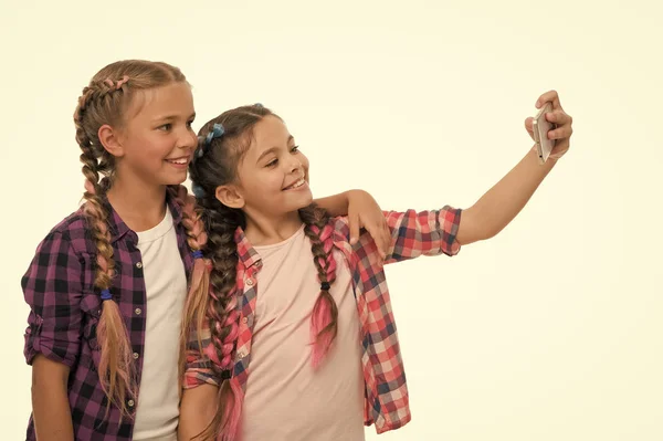 Meisjes schattig kleine kinderen glimlachen naar telefoon scherm. Ze nemen graag selfie voor sociale netwerken. Probleem van de jonge generatie. Afhankelijkheid van mobiele telefoons. Mobiele telefoon en internetverslaving of obsessie — Stockfoto
