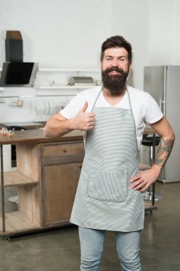 Thumbs up because I like kitchen life. Kitchen inspiration. Attractive kitchen manager. Bearded man smiling and gesturing thumbs up in kitchen. Happy cook wearing apron on show kitchen in restaurant clipart