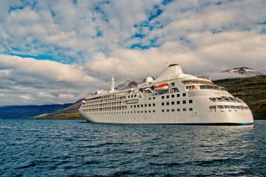 Okyanus gemisi denizde dağ manzarası Sejdisfjordur, İzlanda üzerinde. Cruise gemi denizde dağlar ile bulutlu gökyüzü. Zevk için seyir. Yaz tatil ve gezi. Macera ve keşif