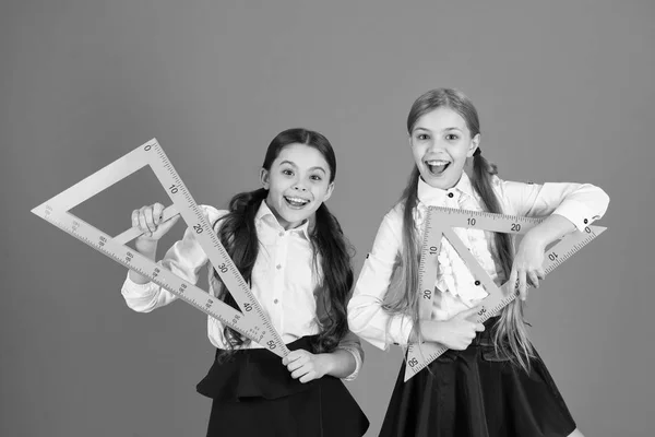 Sin geometría la vida no tiene sentido. Las niñas han vuelto a la escuela. Colegialas lindas sosteniendo triángulos para la lección. Niños en edad escolar con instrumentos de medida. Niñas listas para la lección de geometría —  Fotos de Stock