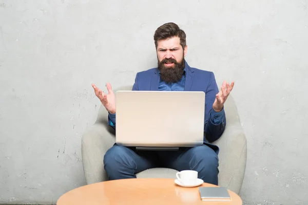 Tener algunos problemas en el trabajo. Hipster bebiendo café y trabajando en la estación de trabajo de computadoras. Hombre barbudo haciendo su trabajo en línea. Trabajar globalmente a distancia —  Fotos de Stock