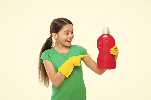 Usando produto de limpeza doméstica. Pequena governanta apontando para garrafa de detergente. Criança gosta de lavar roupa. Ajudante doméstico bonito usando luvas de borracha. Manter as roupas limpas e frescas — Fotografia de Stock