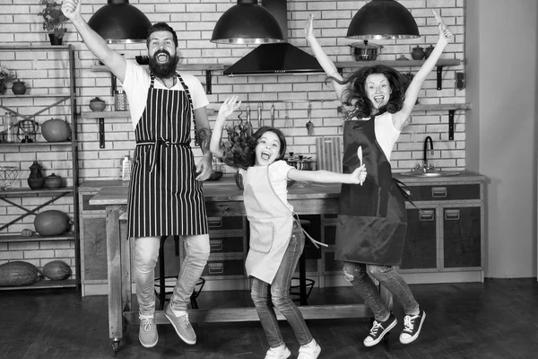 Home party. Happy family jump. Father, mother and child chef cooking. Little girl with parents in apron. Mother and father with little girl. Family day. Happy family in kitchen. Happy family morning