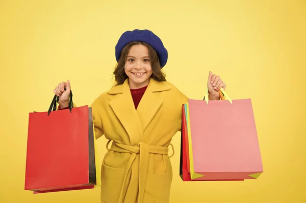 Venta a mitad de temporada. Niña lindo niño mantenga bolsas de compras sobre fondo amarillo. Tienda con tarjeta de descuento. Obtener descuento de compras en cumpleaños o vacaciones. Fashionista adoro ir de compras. Obsesionado con las compras — Foto de Stock