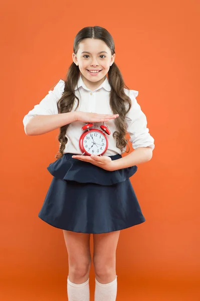 Es de día. horario de rutina diaria. colegiala y despertador retro. Educación infantil. Día del conocimiento. Hora del colegio. Es hora de ir a la escuela. Feliz chica mantenga el despertador contando para la hora del almuerzo — Foto de Stock