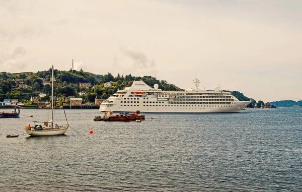 Oban, Regno Unito - 20 febbraio 2010: imbarcazioni in mare lungo la costa montana. Nave da crociera e barche a vela in mare. Viaggiare in acqua. Avventura e scoperta. Vacanze estive e vagabondaggio — Foto Stock