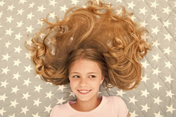 子供の巻き毛リラックス。コンディショナーマスク有機オイルは、髪の光沢と健康を維持します。素晴らしい髪のヒント。翌朝でさえも巻き毛を保つ。女の子子供とともに長いです毛レイ上のベッドトップビュー — ストック写真