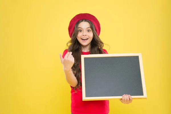 Tableau d'information. Nouvelles de la mode. petite fille enfant avec panneau arrière de l'école, copier l'espace. retour à l'école. Intéressant info. grosses ventes. enfant sur fond jaune. fille heureuse en béret français. petit éditeur — Photo