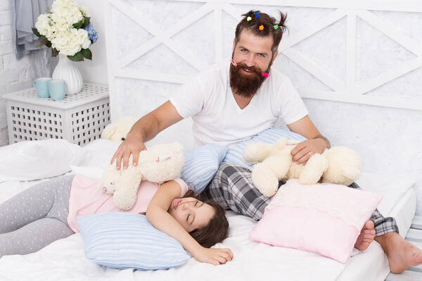 Ending of crazy evening. Having fun pajamas party. Slumber party. Happy fatherhood. Dad and girl relaxing bedroom. Pajamas style. Father bearded man funny hairstyle ponytails and daughter in pajamas