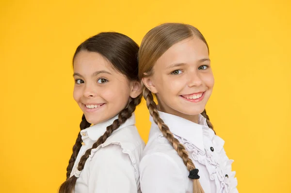 Smarta och smarta. Kid formella mode. Utbildning utomlands. snygga barn. skolkamrater. lyckliga barn i uniform. små flickor på gul bakgrund. vänskap och systerskap. Bästa vänner — Stockfoto