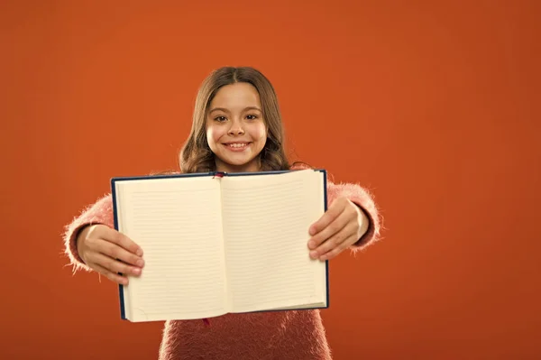 Podívejte se na to. Dívka drží knihu oranžové pozadí. Dítě zobrazit otevřené stránky v knize nebo Poznámkový blok. Kniha koncept store. Zdarma knihy jsou k dispozici ke čtení. Dětské literatury. Rozvoj a vzdělání — Stock fotografie
