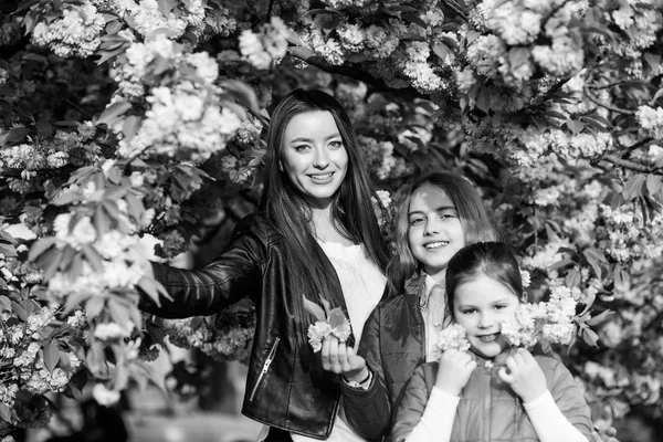 Small children and mother in spring flower. happy sisters in cherry flower. Sakura bloom. family summer. Natural beauty. Mothers day. blossom smell, allergy. Sisterhood. New green life — Stock Photo, Image