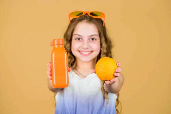 Φυσική πηγή βιταμινών. Το παιδί τρώει πορτοκαλί φρούτα και πίνει χυμό πορτοκάλι. Βιταμίνη διατροφής. Μόδα παιδί γυαλιά ηλίου πίνουν αναζωογονητικό χυμό βιταμίνης. Υγειονομική περίθαλψη. Καλοκαιρινή δίαιτα βιταμινών. Ευτυχισμένη παιδική ηλικία — Φωτογραφία Αρχείου