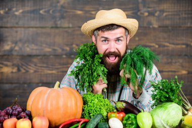 Adam olgun sakallı çiftçi sebze ahşap arka plan tutun. Taze hasat ile çiftçi hasır şapka. Evde yetiştirilen hasat konsepti. Tipik çiftçi adam. Çiftlik pazarı hasat festivali. Sebze sat