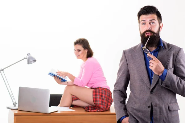 Confident team leader. Confident businessman and sexy secretary sitting on office desk. Confident caucasian man with pretty woman working in background. Confident boss with long beard in formal wear — Stock Photo, Image