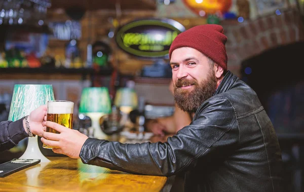 Friday evening. Bar is relaxing place to have drink and relax. Hipster relaxing at bar. Man with beard spend leisure in dark bar. Brutal lonely hipster. Brutal hipster bearded man sit at bar counter