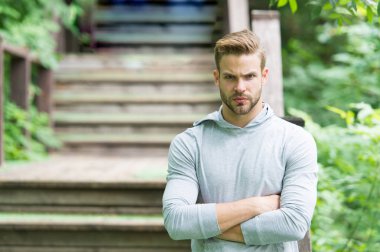 Kaslı ve kendinden emin. Yaz günü kaslı bir adam. Parkın merdivenlerinde kaslı kollarını çapraz tutan atletik adam. Yakışıklı sporcu ya da sporcu kas gücü ve gücü gösteriyor.
