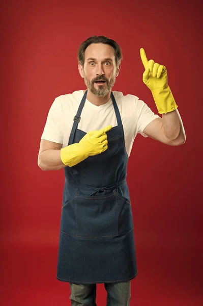 Bara titta där. Mogen man pekar finger i gula handskar. Mogen hushållens arbetaren presentera något. Senior mannen bära Haklapp förkläde och gummihandskar. Att ge hushåll service — Stockfoto