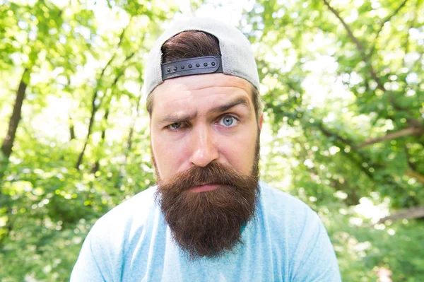 Bearded macho. Hipster with long beard emotional face close up nature background. Brutal male leisure. Summer travel. Serious bearded mature man in natural environment. Bearded guy in park forest — Stock Photo, Image