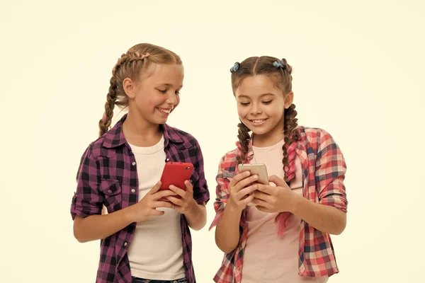 Girls cute small children smiling to phone screen. They like internet surfing social networks. Problem of young generation. Mobile phone and internet addiction or obsession. Mobile phone dependence