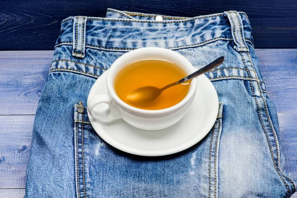 Gesunde Gewohnheiten. Teezeitkonzept. Tasse Becher heißes Wasser und Beutel Tee vorhanden. Becher gefüllt mit kochendem Wasser und Teebeutel auf blauem Jeans-Hintergrund. Prozess Teeaufbrühen in Keramikbecher. pflanzliches grünes oder schwarzes Ganzblatt — Stockfoto