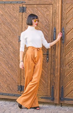 Kız makyaj moda giysiler içinde poz ile. Şık kıyafet ince uzun bayan. Kadın gevşek pantolon yürüyüş. Kadın moda esmer açık havada ahşap arka plan ayakta. Moda ve stil kavramı