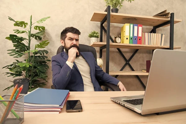 Developing business strategy. Risky business. Concentration and focus. Man bearded boss sit office with laptop. Manager solving business problems. Businessman in charge of business solutions