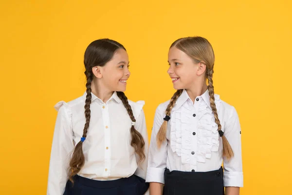 Amiamo studiare. bambini felici in uniforme. bambine su sfondo giallo. amicizia e sorellanza. Migliori amici. Moda formale per bambini. Istruzione all'estero. bambini dall'aspetto intelligente. amici di scuola — Foto Stock