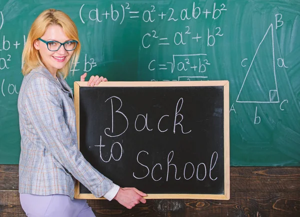 Super début d'année scolaire. Meilleures façons d'accueillir les élèves à l'école. La maîtresse garde l'inscription au tableau noir à l'école. C'est encore l'heure de l'école. Professeur d'école heureux bienvenue élèves — Photo