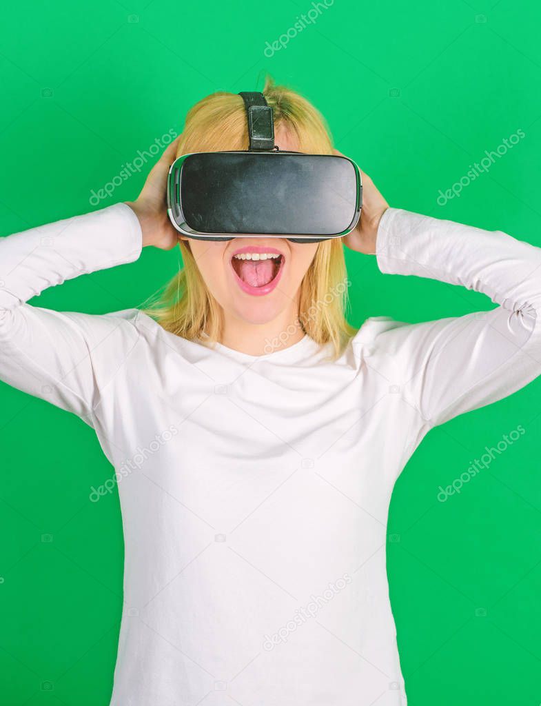 Funny young woman with VR. Woman wearing virtual reality goggles in green background. Amazed young woman touching the air during the VR experience. Smartphone using with VR headset.