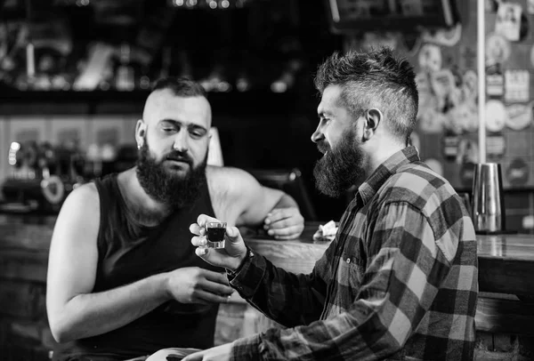 Friday relax in pub. Friends relaxing in pub. Drunk conversation. Cheers concept. Hipster brutal bearded man drinking alcohol with friend at bar counter. Men relaxing at pub. Strong alcohol drinks — Stock Photo, Image