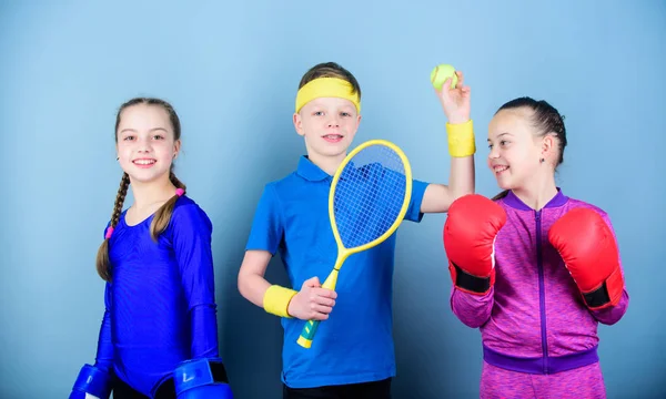 Amici pronti per l'allenamento sportivo. Il bambino potrebbe eccellere in sport completamente diversi. Fratelli sportivi. Ragazze bambini con attrezzature sportive di boxe e giocatore di tennis ragazzo. Modi per aiutare i bambini a trovare lo sport di cui godono — Foto Stock