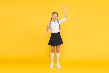Emotional schoolgirl. Celebrate knowledge day. September time to study. Girl adorable pupil on yellow background. School uniform and fashion. Back to school. Student little kid adores school clipart