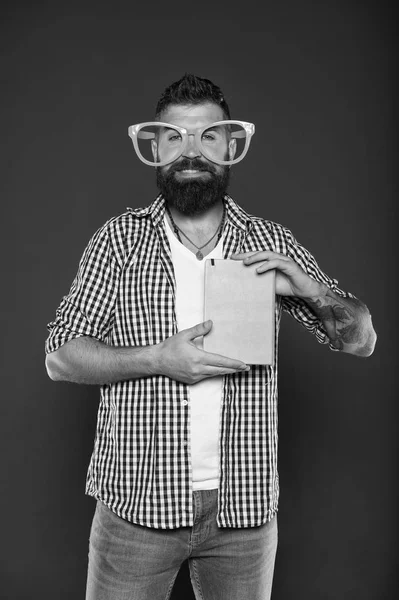 Βιβλιοφάγος. Σπασίκλα βιβλίο φορώντας φανταχτερά γυαλιά. Μελέτη σπασίκλα βιβλίο εκμετάλλευση. Αρσενικό φοιτητής πανεπιστημίου με σημειώσεις. Γενειοφόρος άνδρας κόμμα γυαλιά με το βιβλίο του μαθήματος — Φωτογραφία Αρχείου
