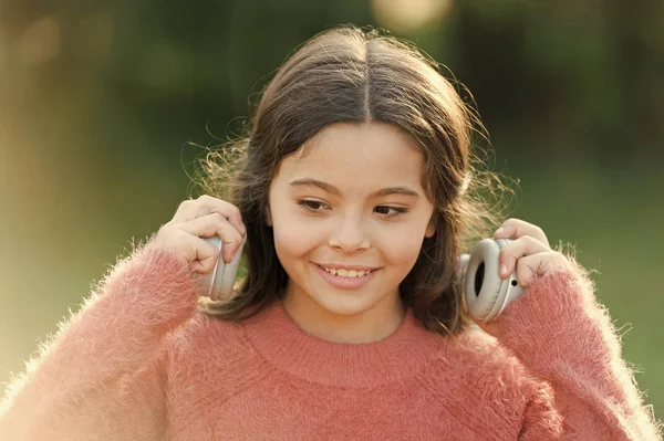 Experimentando um som excelente com nova tecnologia. Criança feliz gosta de ouvir música em movimento. Menina adorável ao ar livre. Menina criança usando fones de ouvido. Ela só quer ouvir música. — Fotografia de Stock