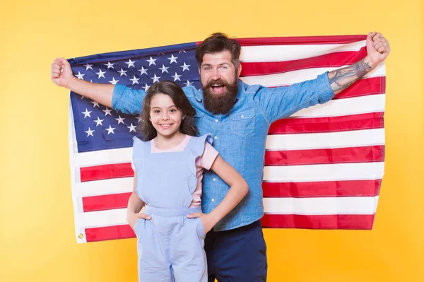 ¿Cómo celebran los americanos el día de la independencia? Familia patriótica alegre y amigable. Vacaciones de día de independencia. La independencia es felicidad. Padre barbudo hipster y linda hijita con bandera de EE.UU. — Foto de Stock