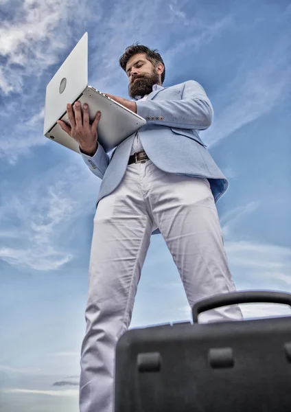 Guy formal suit modern technology manager entrepreneur. Modern communications. Man well groomed bearded hipster holds laptop blue sky background. Top qualities of excellent manager. Keep in touch