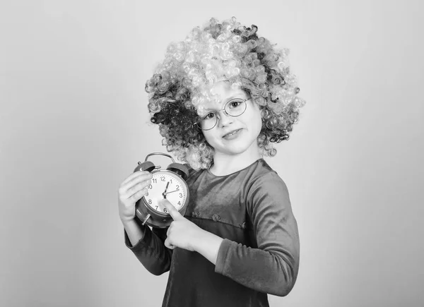 Kinderopvang. Gelukkige momenten. Kid Hold alarm clock. Ophouden zo ernstig te zijn. Meisje schattig speelse Kid dragen krullend regenboog pruik. Het leven is leuk. Gelukkige kindertijd. Gelukkig klein meisje. Internationale Kinder dag — Stockfoto