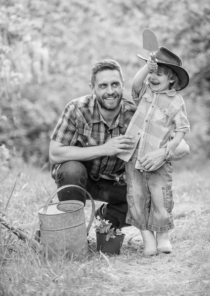 small boy child help father in farming. watering can, pot and hoe. Garden equipment. father and son in cowboy hat on ranch. happy earth day. Family tree nursering. Eco farm. Good-looking gardener