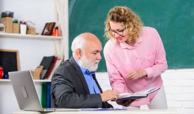 Öğretmene görev hakkında sorular soran öğrenci. Eğitimci ve öğrenci kitaba bakıyor. Zor bilgileri açıklıyor. Matematik görevlerini çözmek. Kitap kaynağı bilgisi. Okul kitap konsepti. Lütfen bana yardım et. Ev ödevini kontrol edin