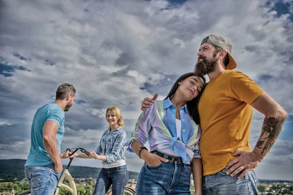 Concept de service de location de vélos. Va chercher un vélo pour ta copine. Couple avec vélo passer un bon moment tandis qu'un autre couple s'ennuyait. Louez un vélo et amusez-vous. Couples passent loisirs manière différente ciel fond — Photo