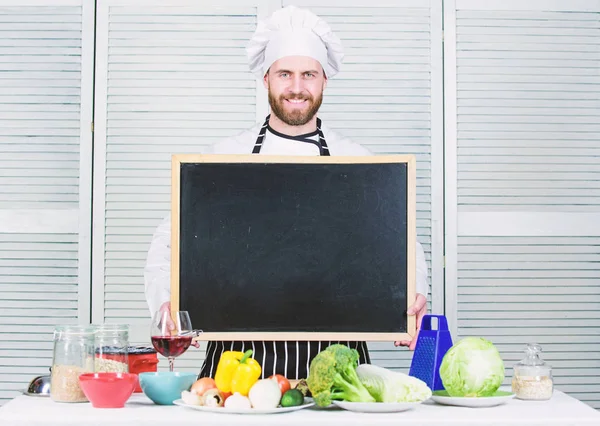 Escuela culinaria. Jefe de cocina enseñando clase magistral en la escuela de cocina. Maestro cocinero dando clases de cocina. Educación en cocina y preparación de alimentos. Hombre con sombrero de chef sosteniendo pizarra vacía, espacio para copiar — Foto de Stock