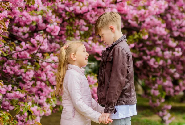 Verliebte Kinder blühen rosa Kirschblüten. Liebe liegt in der Luft. Paar entzückende schöne Kinder gehen Sakura Garten. Zärtliche Liebesgefühle. Mädchen und Junge. romantisches Date im Park. Frühlingszeit zum Verlieben — Stockfoto