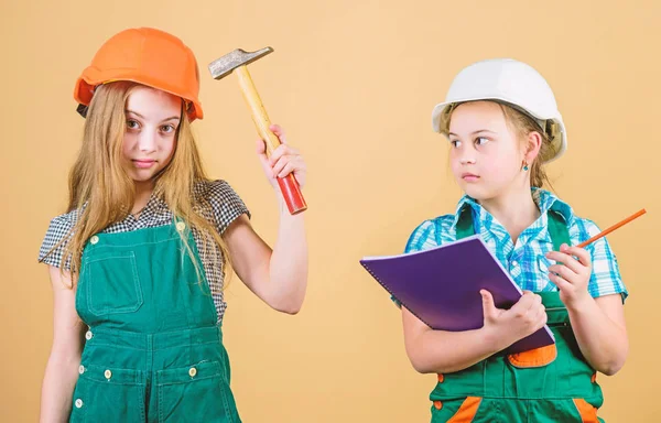 Little kids in helmet with hammer. Labor day. 1 may. happy children. Future career. Foreman inspector. Repair. small girls repairing together in workshop. Feeling tired after hard day in repair shop