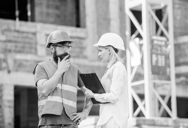 Construction project management. Building industrial project. Construction industry concept. Discuss progress project. Woman engineer and bearded brutal builder discuss construction progress
