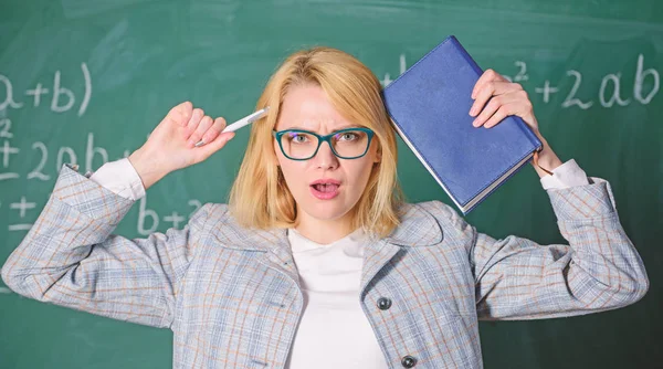 Overwork and lack of support driving teacher out of profession. Teacher woman with book chalkboard background. Why teacher quit off sick with stress. School toxic routine. Teacher stress and burnout