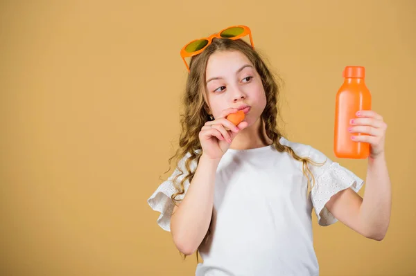 Summer vitamin diet. Happy childhood. Natural vitamin source. Vitamin nutrition. Fashion kid sunglasses drink refreshing vitamin juice. Health care. Girl eat carrot vegetable and drink carrot juice