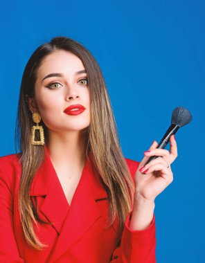Hırslı ve güzel. Güzellik ve moda. Mücevher küpeleri. Kırmızı ceketli kız. Saç güzellik salonu ve kuaför salonu. Bir kadının moda portresi. Profesyonel makyaj fırçası olan seksi bir kadın.