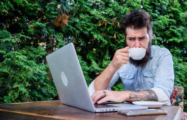 İnternet kafeyi ziyaret etmek. Hipster açık hava kafede çay ve ücretsiz wifi tadını çıkarın. Sakallı adam içki içip kafede internette geziniyor. İnternet erişimi ve taze demlenmiş kahve sağlayan siber kafe